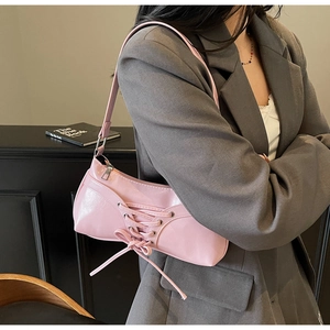 Pink bow shoulder bag made of shiny faux leather shown as an elegant underarm style