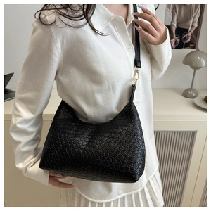 Close-up view of a stylish black woven PU underarm bag carried by a fashion model