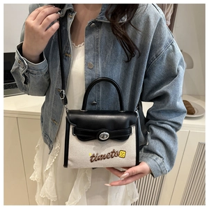 Detail shot of canvas and black leather crossbody bag with silver rotating metal lock