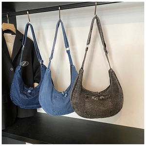 Three colors of denim hobo bags hanging with decorative pockets and tassel zippers