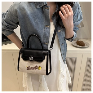 Crossbody view of beige canvas and black leather handbag with embroidered timeto text