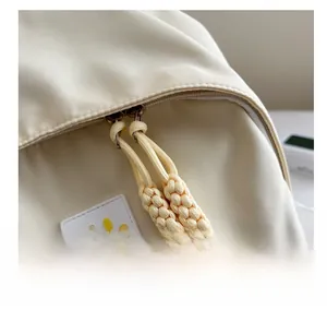 Detail of smooth double zippers and yellow smiley face patch on beige backpack