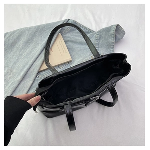 Detail view of the black patent leather shoulder bag interior with zippered compartment