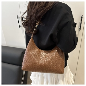 Detail view of the brown woven PU leather hobo bag worn as a stylish underarm bag