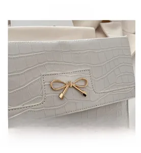 Detail of white stone pattern PU leather handbag with elegant gold bow metal clasp closure