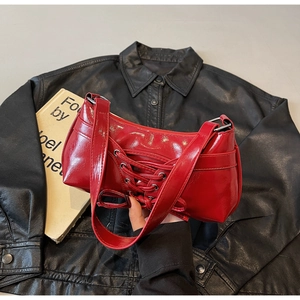 Detailed close-up of bright red patent leather underarm bag with decorative lace-up bow