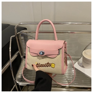 Close-up of pink and beige canvas handbag with bear embroidery and metal clasp detail