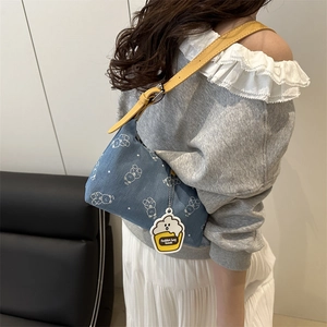 Blue denim underarm bag with bear print and yellow adjustable leather strap on model
