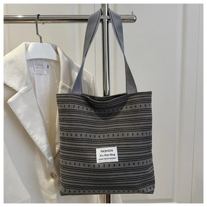 Vue détaillée du sac cabas tissé à rayures grises avec étiquette blanche et anses plates