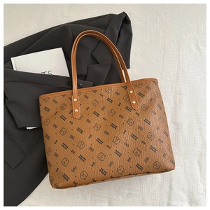 Detail of brown leather tote bag with bear print and sturdy gold rivet handle straps