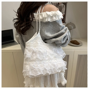 Close-up of white lace tote bag with tiered ruffles and delicate handle detail