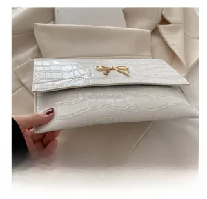 Macro shot of white crocodile embossed leather and golden bow metal buckle detail