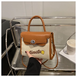 Detail of canvas and leather patchwork bag with timeto embroidery and rotating metal lock