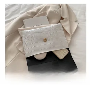 Macro detail of white crocodile-embossed PU leather clutch bag with interior storage space