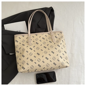 Close-up of beige tote bag with black bear prints and textured leather detail