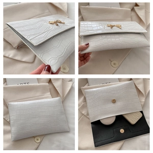 Detail showing white crocodile texture bag with gold bow clasp and inner storage space