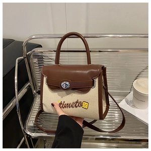 Detail of canvas handbag with brown leather flap and 'timeto' embroidery on front