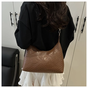 Detailed back view of a stylish brown woven PU leather underarm tote bag on a model
