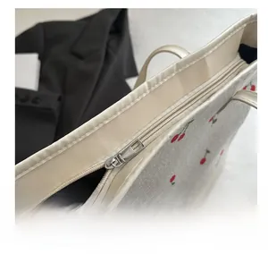 Gros plan sur la fermeture éclair argentée d'un sac cabas en velours côtelé à motif cerise