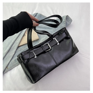 Close-up of black glossy underarm bag featuring silver metal buckle and sleek strap detail