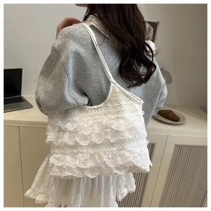 Detailed view of a white lace tiered ruffle shoulder bag on a model in a cozy cafe