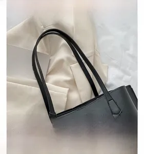 Detail of reinforced black leather straps and stitching on a large tote bag
