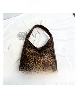 Close-up of leopard print fabric texture and brown leather shoulder strap on tote bag