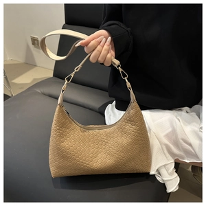 Detailed close-up of the elegant woven pattern on a tan PU leather underarm bag