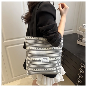 Détail du sac cabas en toile montrant le motif rayé et l'étiquette FASHION à l'avant