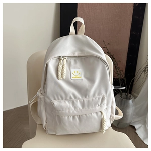 Detail of cream white backpack with yellow smiley face patch and side drawstring pocket