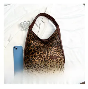 Detail of leopard print tote bag with brown leather trim shown next to a smartphone