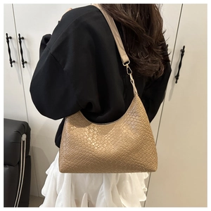 Close-up detail of a stylish woven brown PU leather underarm bag on a model's shoulder