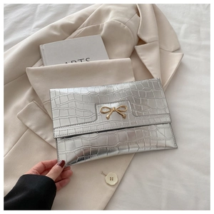 Close-up of silver stone pattern PU clutch with elegant golden bow metal buckle detail