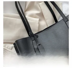 Detailed close-up of precise stitching on black soft leather tote bag handle