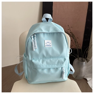 Detailed view of light blue nylon backpack with front pocket and smiley face logo