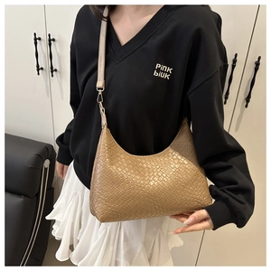 Detailed view of a khaki woven PU leather underarm bag held by a fashion model