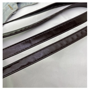 Macro shot of dark brown glossy leather strap with detailed stitching on shoulder bag