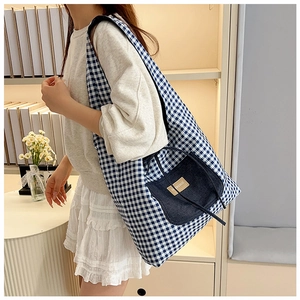 Detail of blue plaid canvas tote bag with denim front pocket and label shown on model