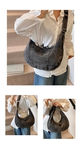 Detail of vintage washed denim hobo bag featuring utility pockets and adjustable strap