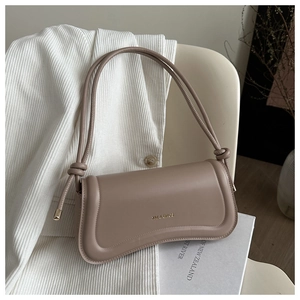 Close-up of taupe handbag with XM & BAGS metal logo and elegant knotted shoulder strap