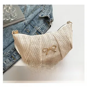 Close-up of beige woven crescent bag with golden bow hardware and textured pattern