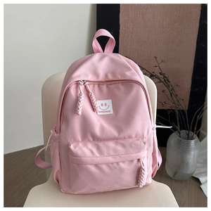 Detailed view of pink nylon school backpack with fashion patch on a cream chair