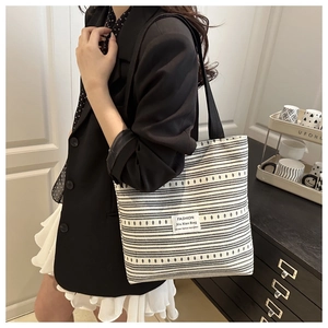 Détail du sac cabas en toile rayée avec étiquette en tissu et texture tissée