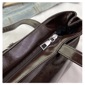 Macro shot of silver zipper closure and vintage texture on dark brown tote bag