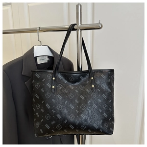 Detail of black tote bag with cartoon bear print and golden rivets on metal hanger