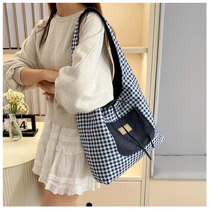 Detail of blue checkerboard tote bag featuring a denim front pocket and fashion label
