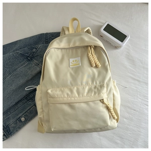 Détail du sac à dos crème avec patch smiley et tirettes de fermeture éclair tressées