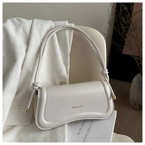 Detailed view of cream leather shoulder bag with decorative knotted strap and gold logo