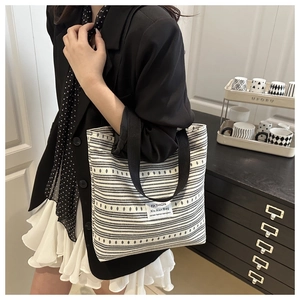 Détail du sac cabas en toile avec motifs rétro et étiquette de marque porté