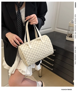 Dettaglio di una borsa Boston crema con stampa M tenuta da una modella in un interno
